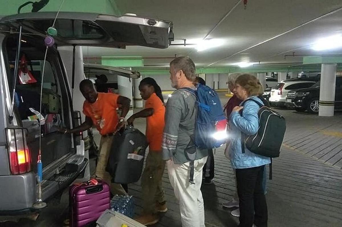 a group of people loading luggage into the back of a car