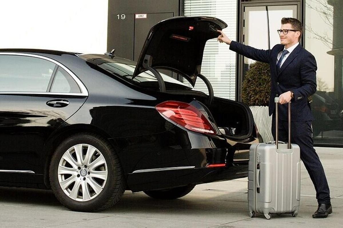một người đàn ông với một chiếc vali đứng cạnh một chiếc xe hơi
