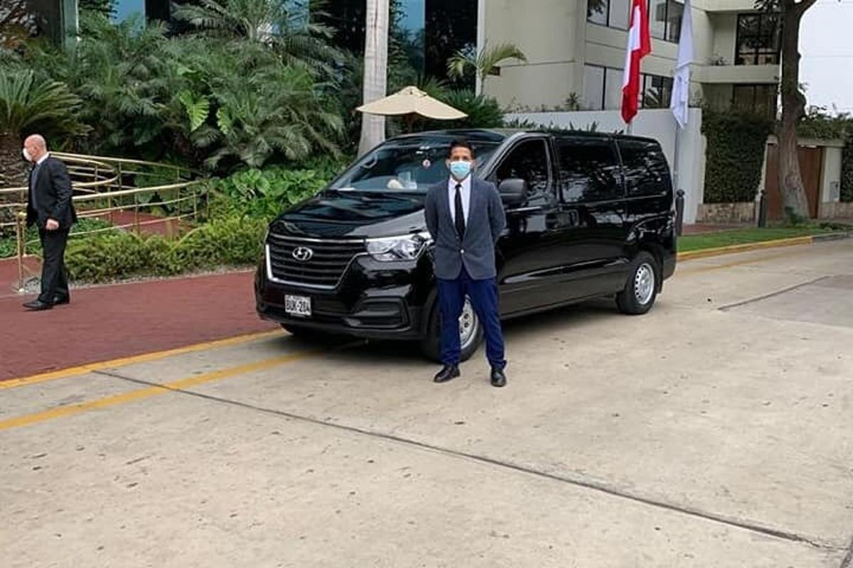 seorang pria bertopeng berdiri di samping mobil van hitam