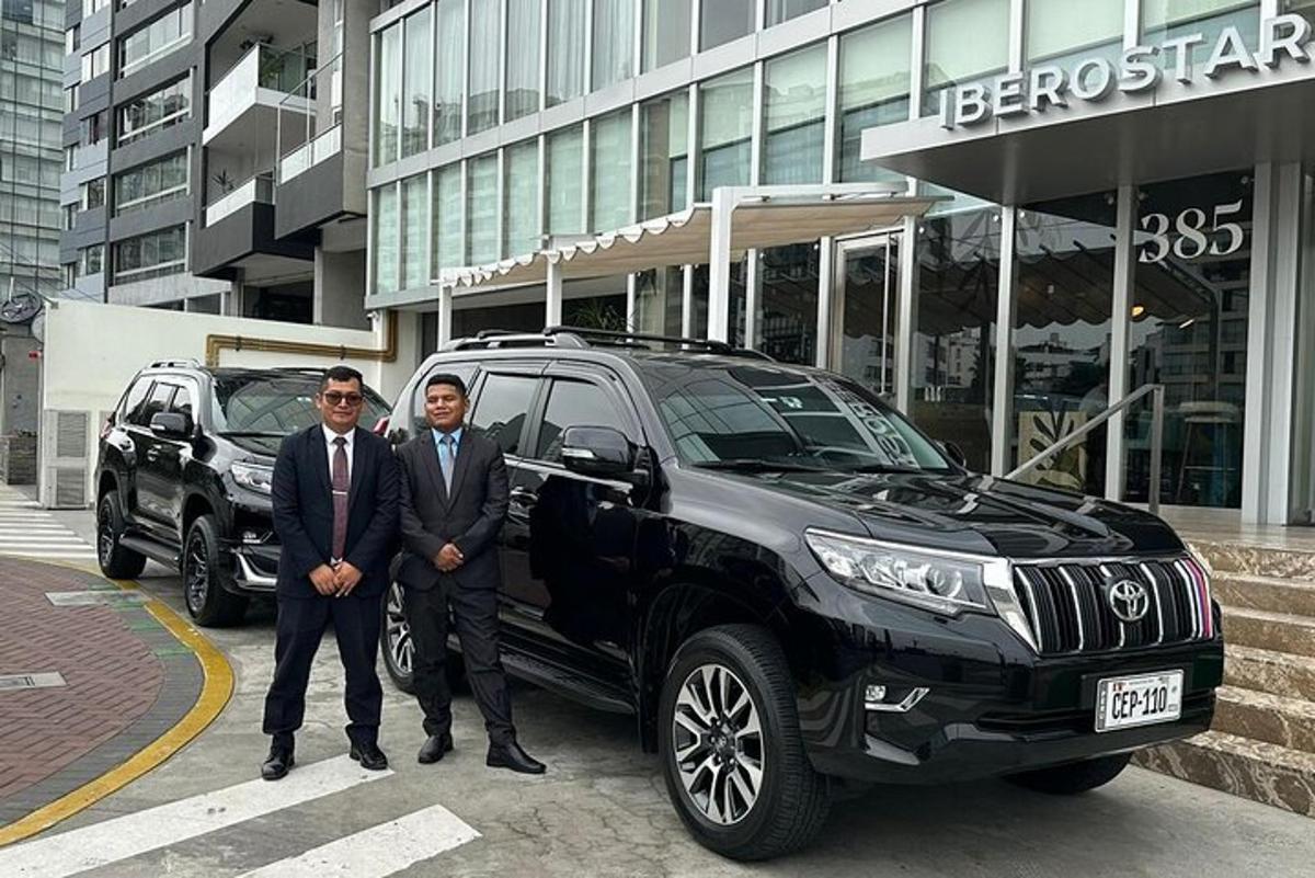 two men in suits standing next to a black truck