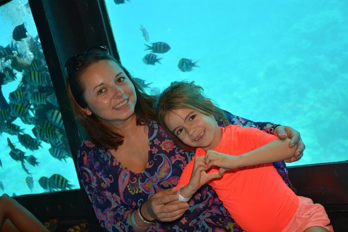 a woman and a little girl sitting next to a aquarium