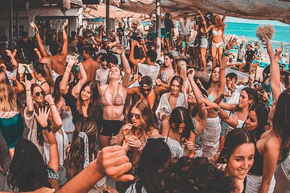 skupina ljudi, ki stojijo na plaži z rokami v zraku