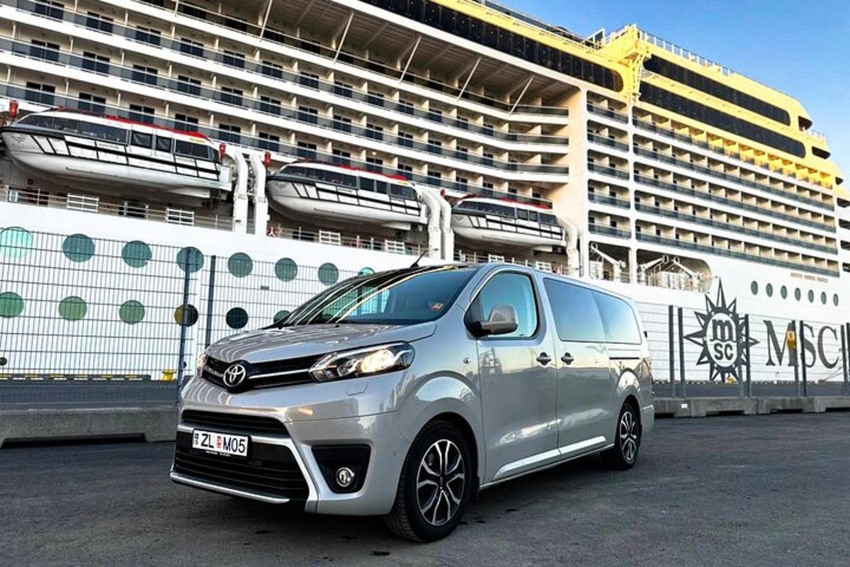 a silver car parked in front of a cruise ship