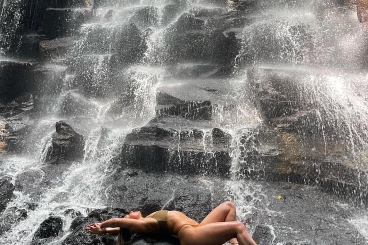 a woman laying on the ground next to a waterfall