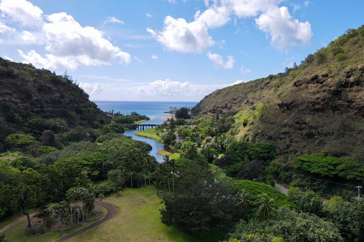 Una vista de un río entre dos colinas con el océano.