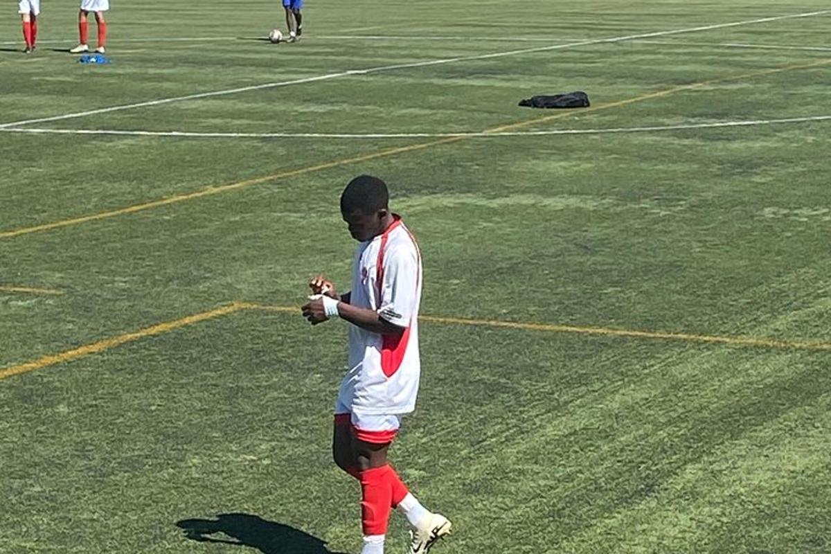 un uomo in piedi su un campo da calcio che guarda il suo cellulare