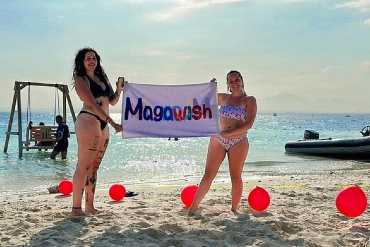 Dos mujeres en traje de baño sosteniendo un cartel en la playa