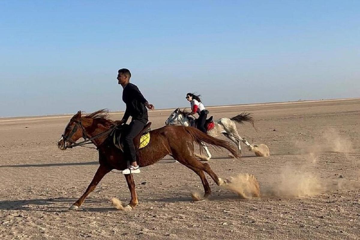 dos personas montando a caballo en el desierto