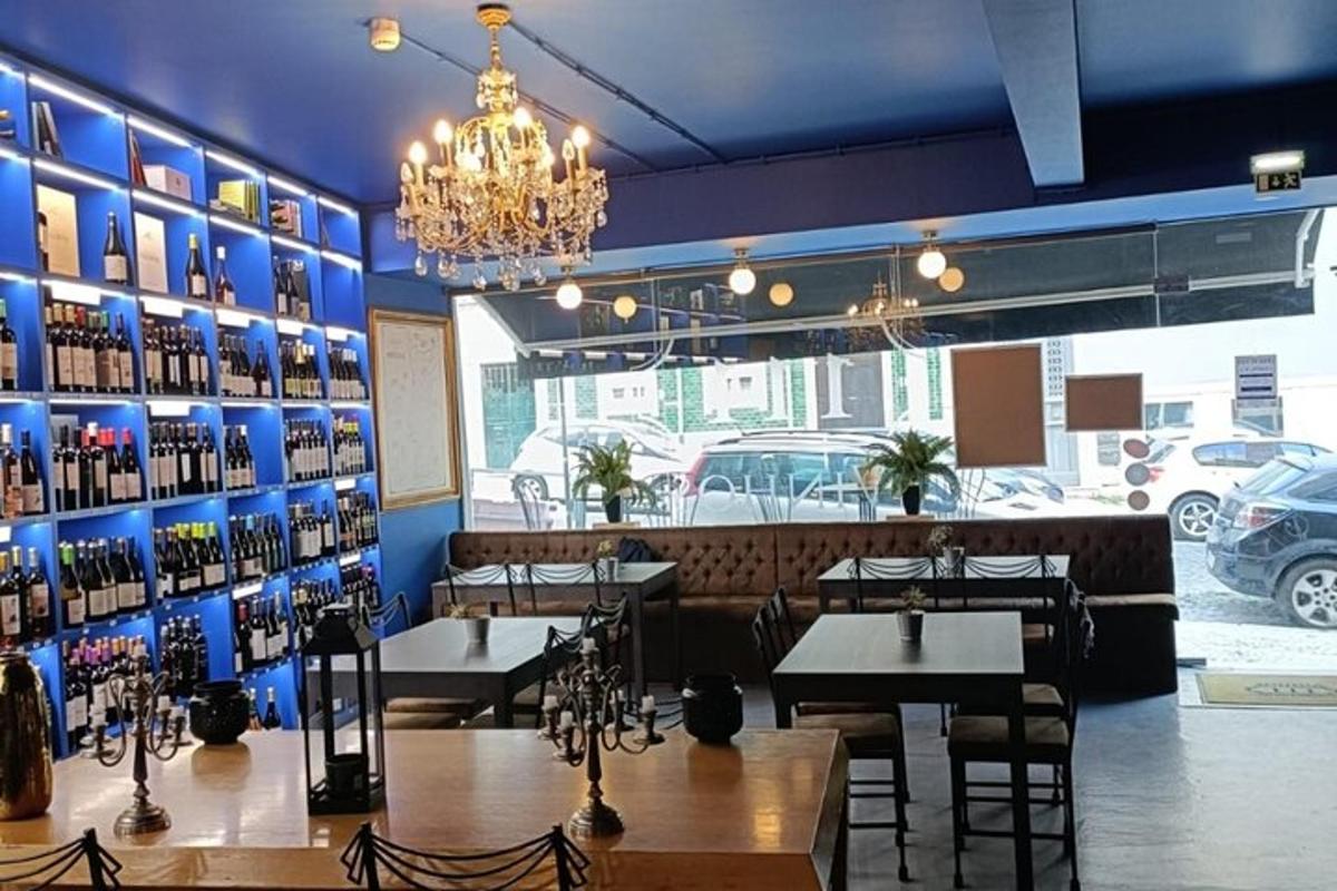 restaurace se stoly a židlemi a stěnou plnou vinných lahví