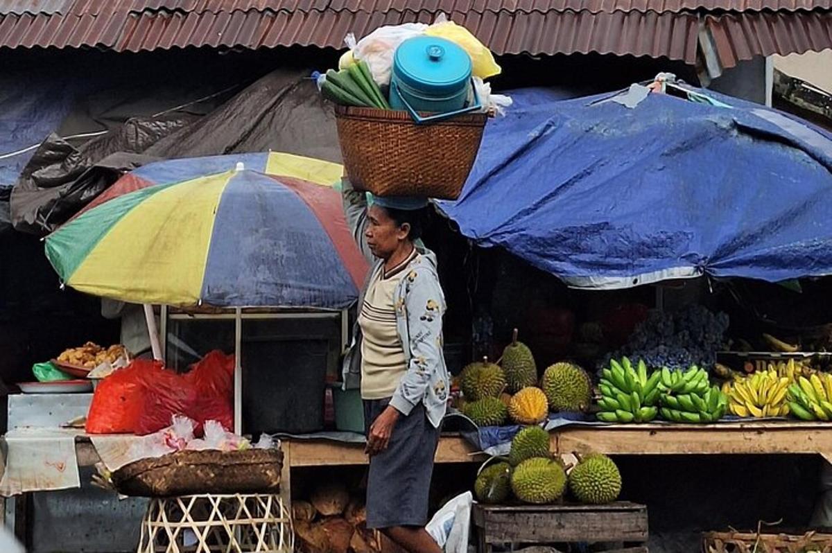 một người phụ nữ đứng trước một quầy bán trái cây với một chiếc giỏ trên đầu