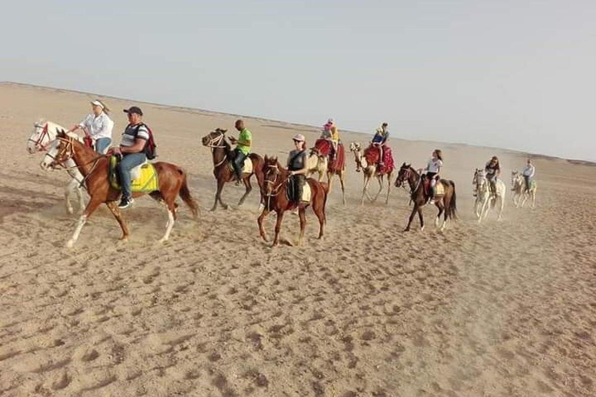 a group of people riding horses in the desert