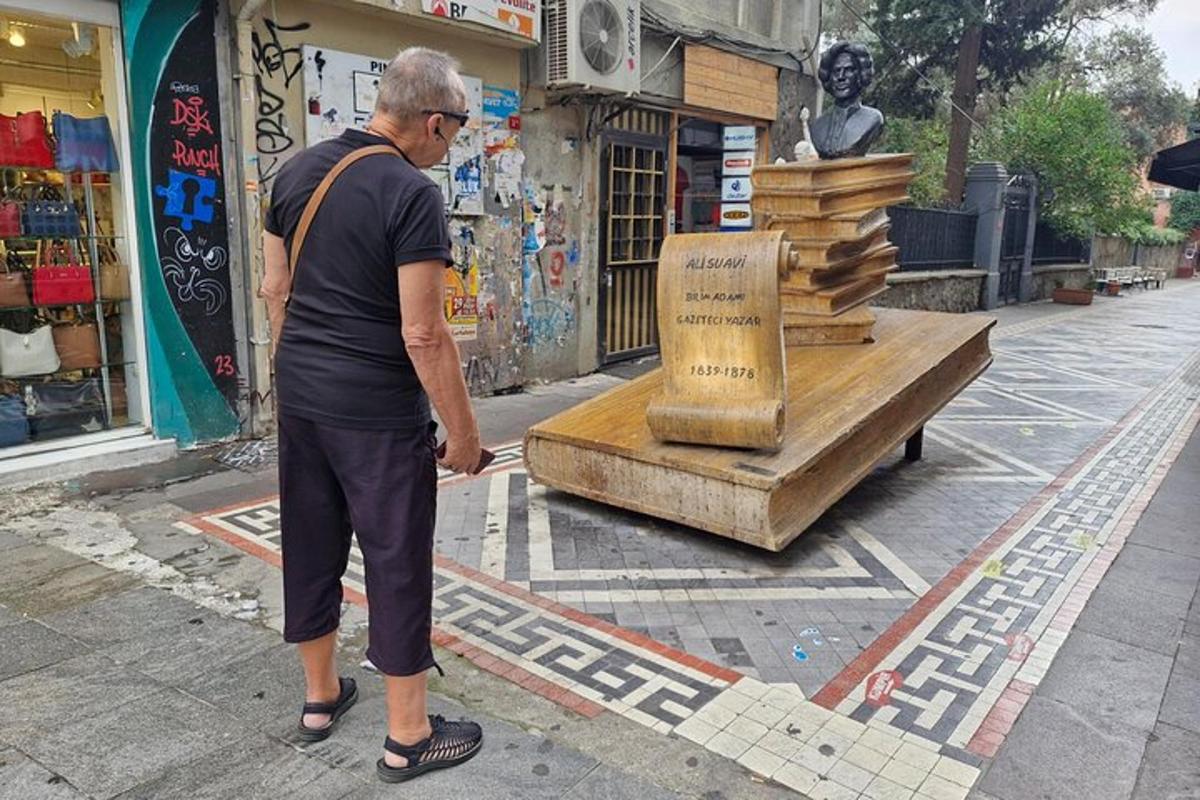 muž stojící vedle hromady knih na ulici