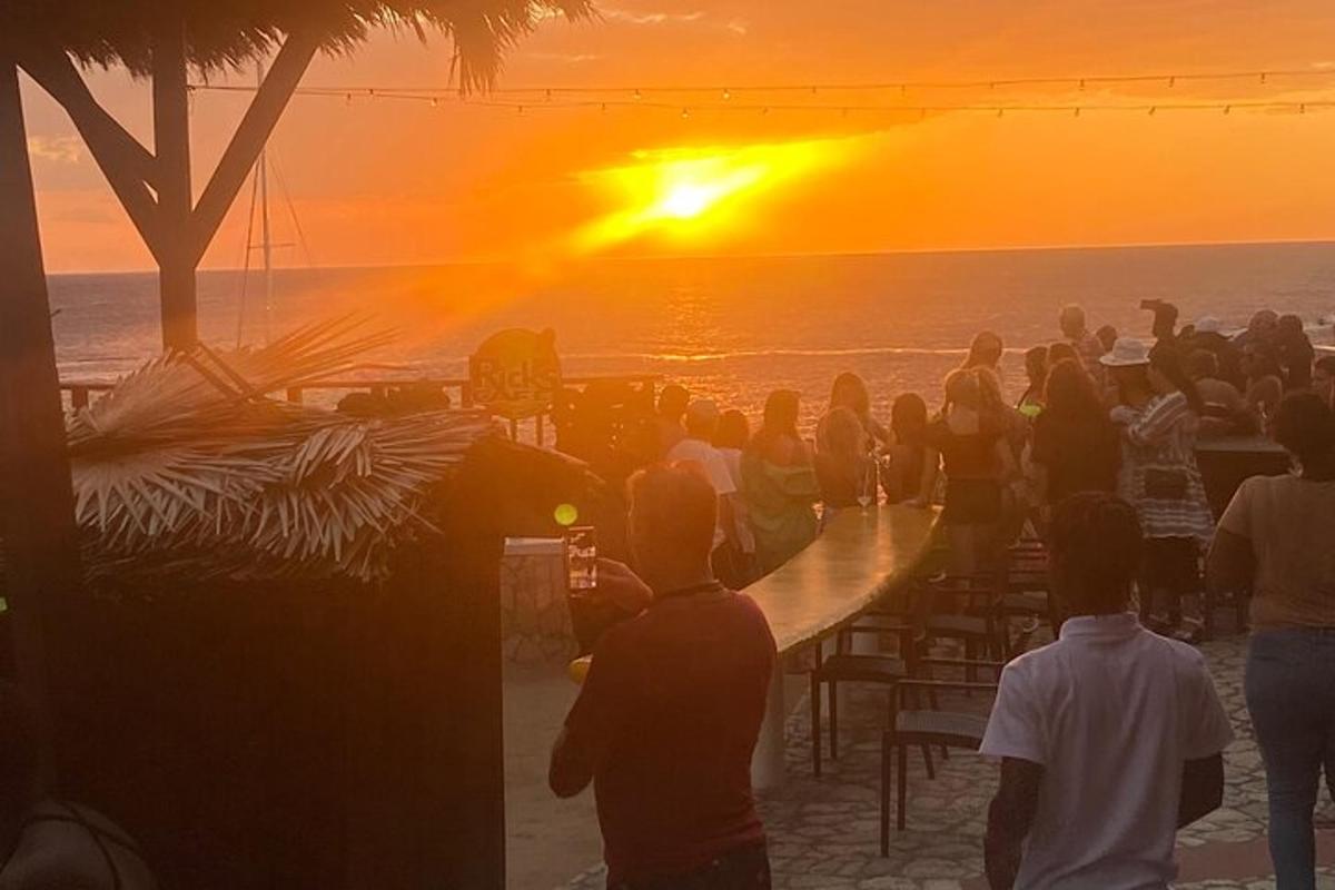 sekelompok orang menyaksikan matahari terbenam di pantai
