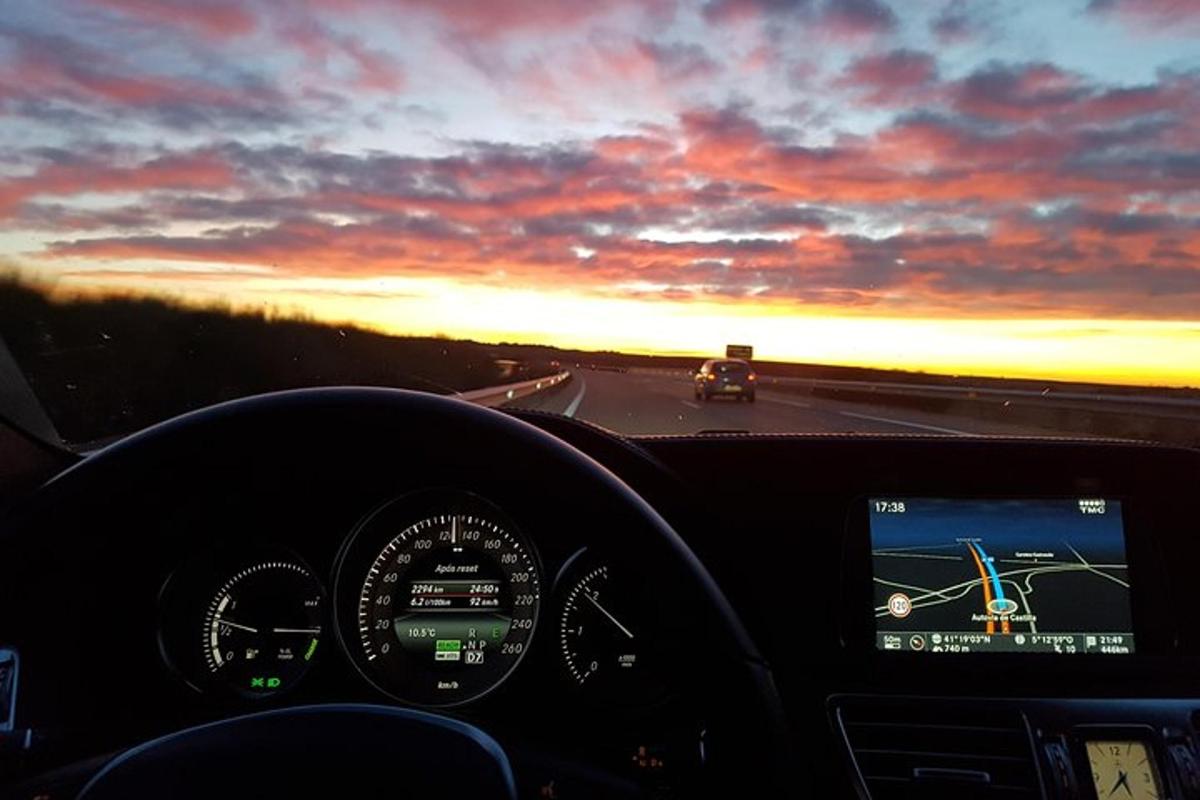 a view of a car driving down a highway at sunset