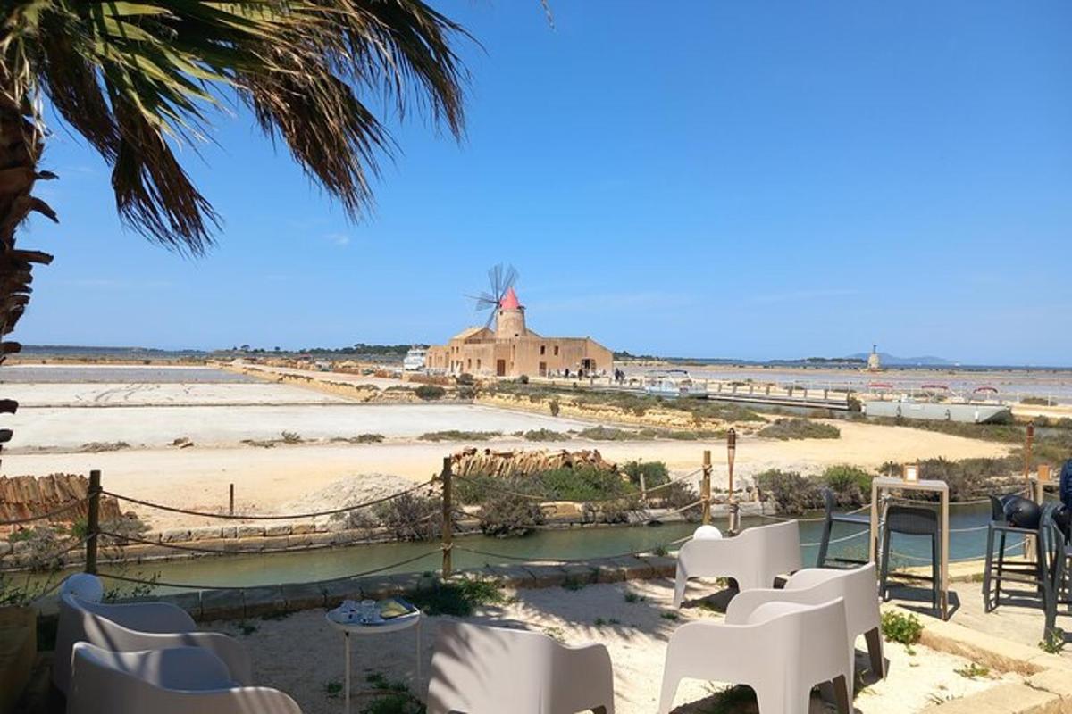 Una vista de una playa con sillas blancas y un molino de viento.