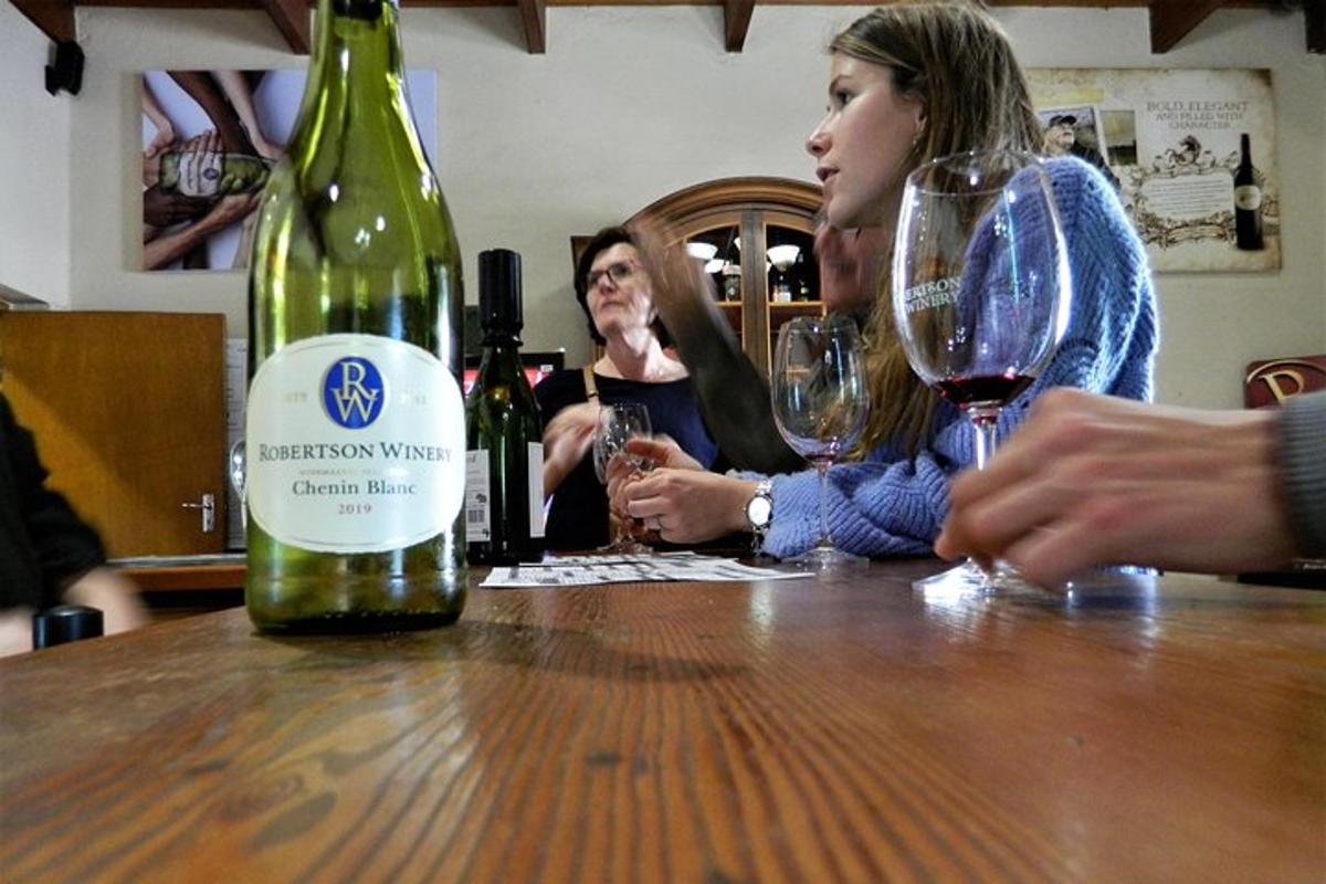 a group of people sitting at a table with a bottle of wine