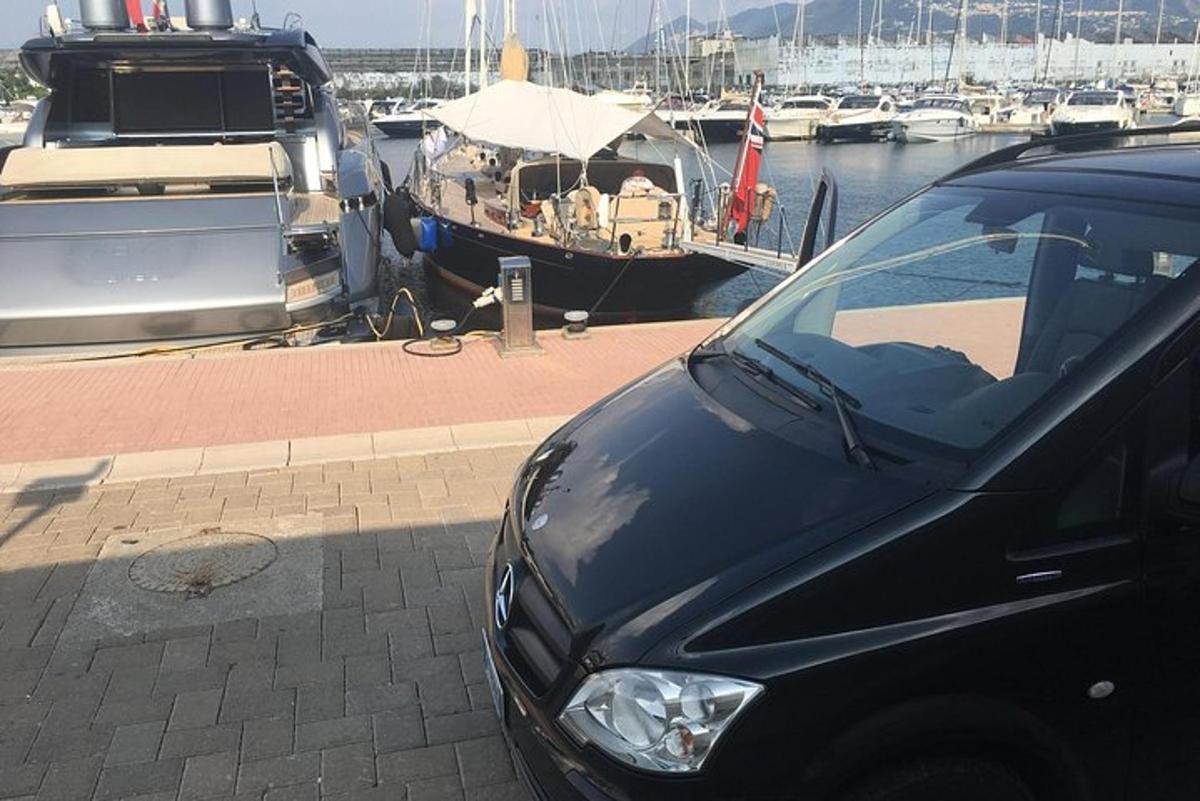 musta auto pysäköitynä venesataman viereen veneiden kanssa