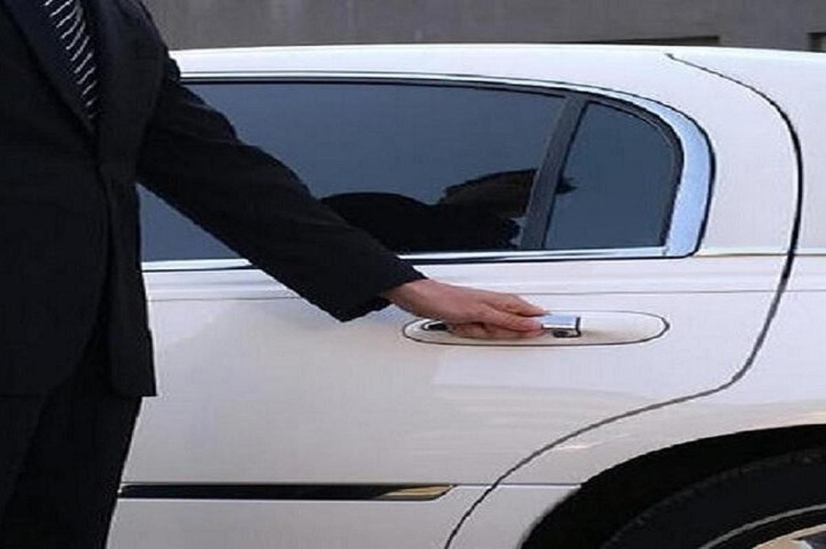 un uomo in giacca e cravatta che apre la portiera di un'auto bianca