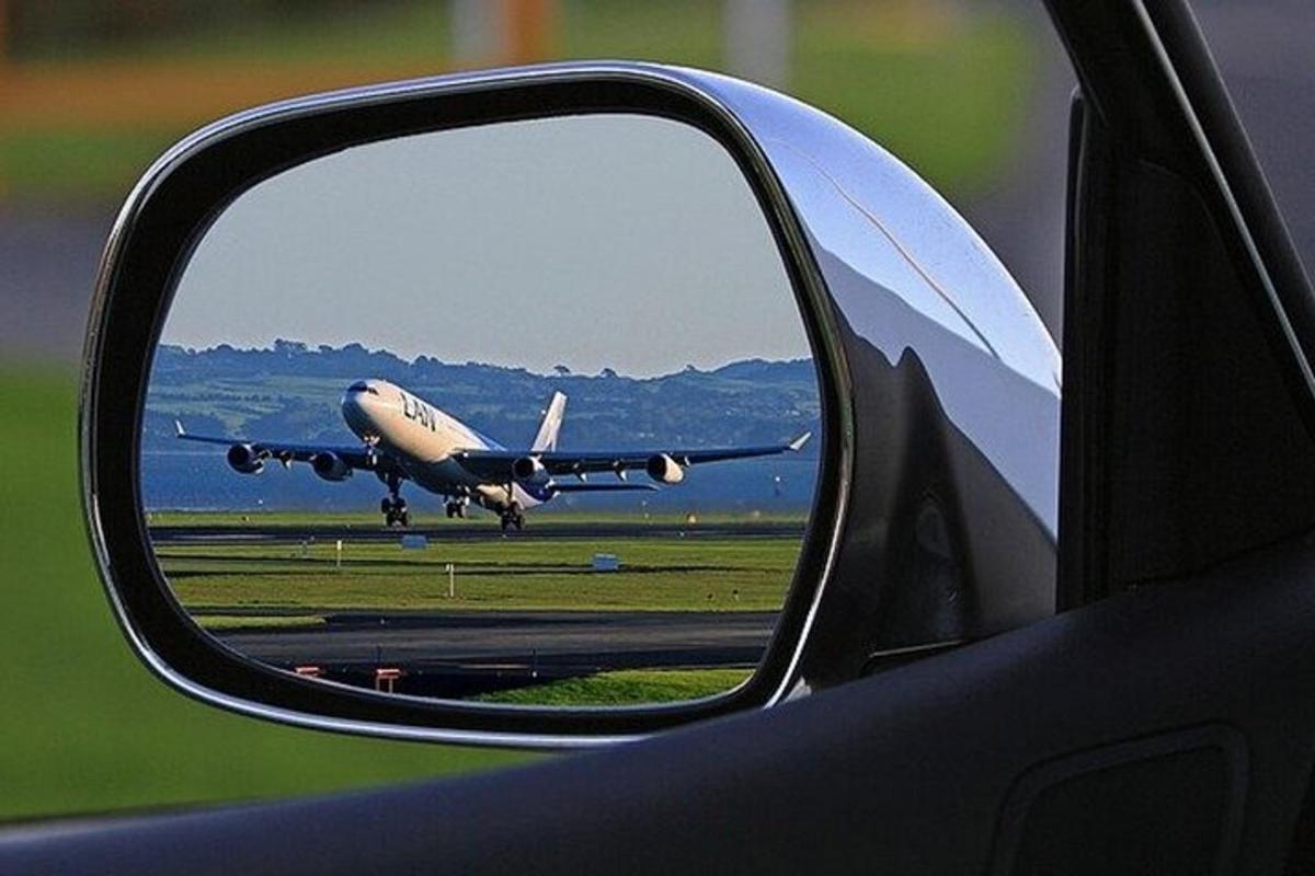 una vista di un aereo nello specchietto retrovisore laterale di un'auto