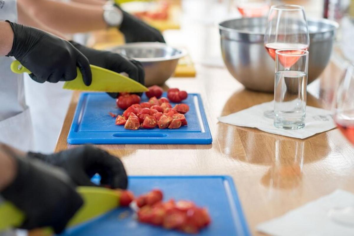 Una persona con guantes negros cortando fresas en una mesa.