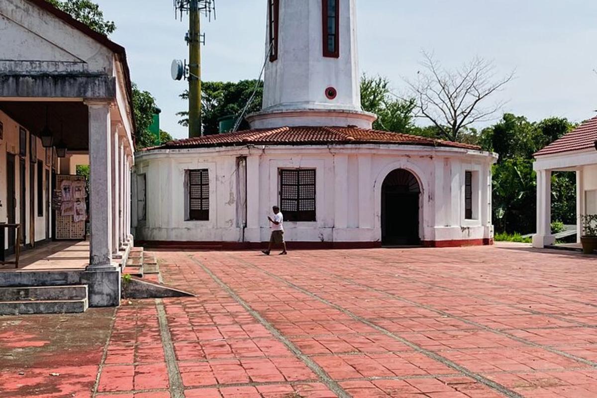 osoba kráčející před bílou budovou s hodinovou věží