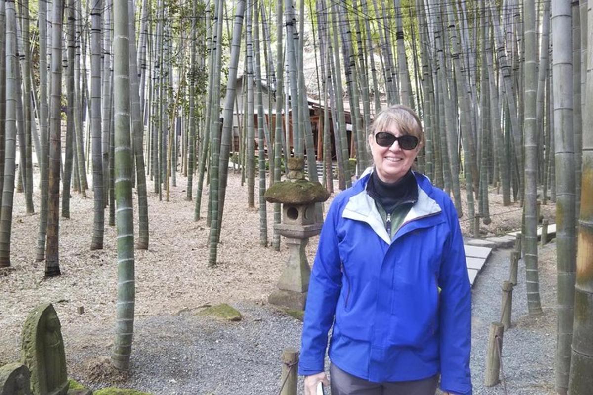 Una mujer está parada en un bosque de bambú.