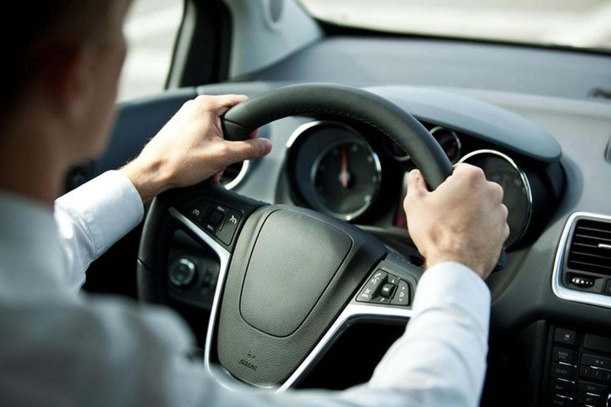 muž řídící auto s rukama na volantu