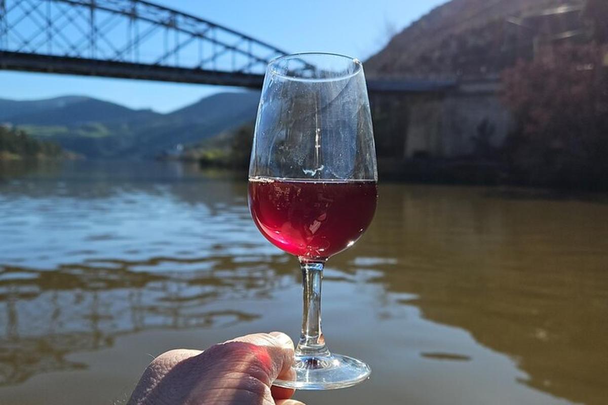 una persona sosteniendo una copa de vino frente a un río
