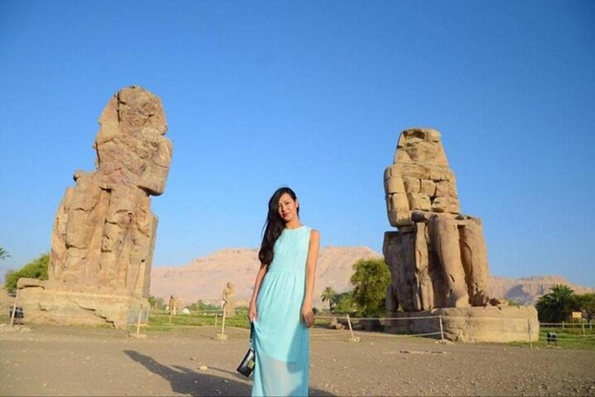 uma mulher de vestido azul parada em frente a algumas pedras