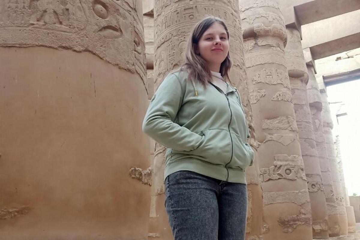 una dona dempeus davant d'un pilar de pedra