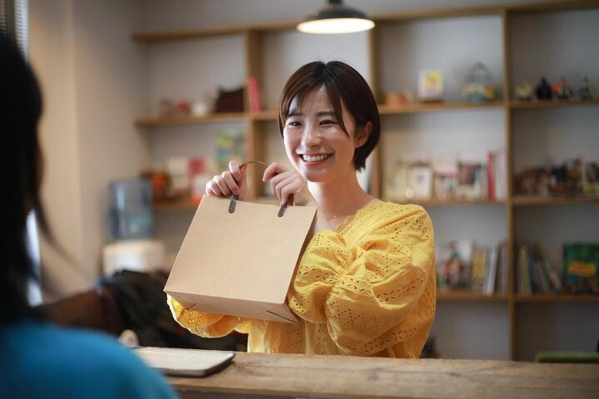 Una mujer sentada en una mesa sosteniendo un trozo de papel.