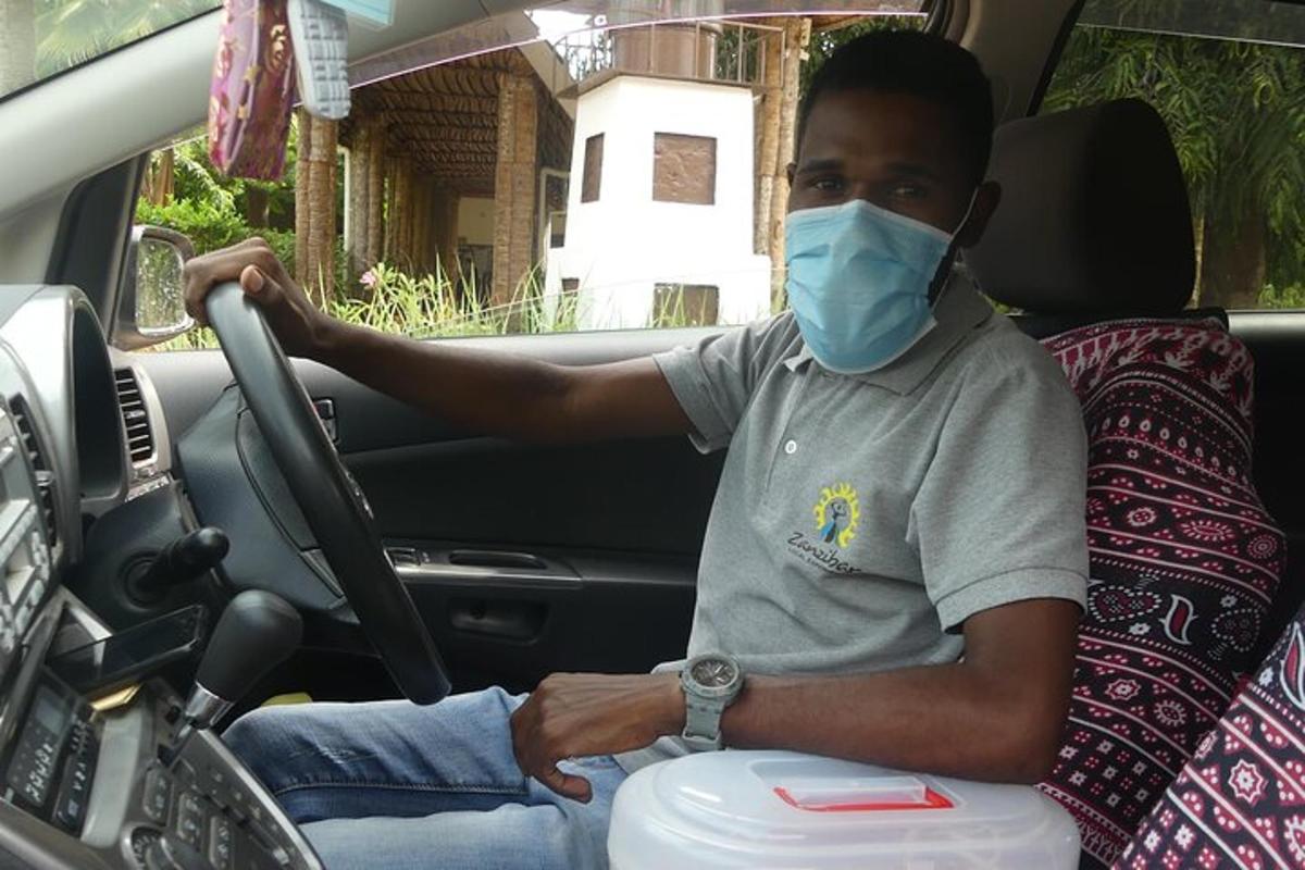 ein Mann, der mit einer Maske im Gesicht Auto fährt