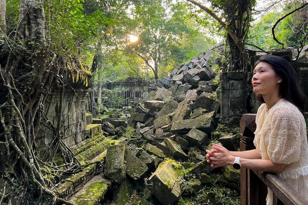 a woman standing on a fence looking at a garden