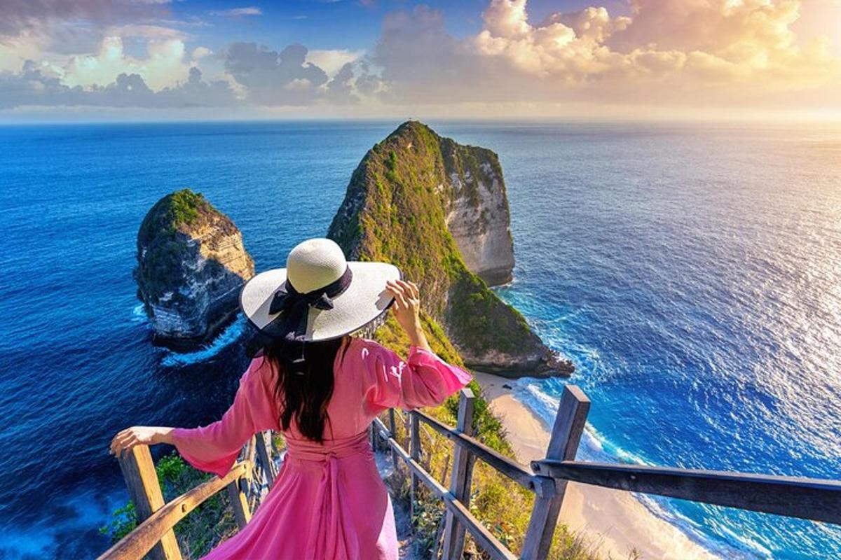 eine Frau in einem rosa Kleid mit Blick auf das Meer