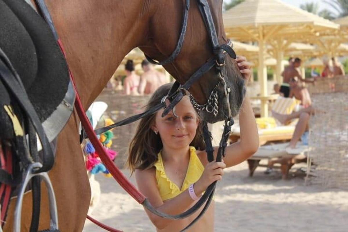 egy fiatal lány állt egy barna ló mellett
