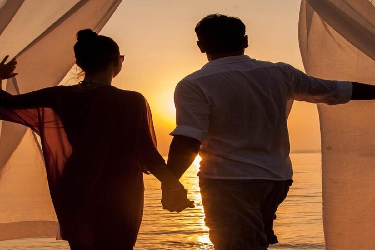 moški in ženska, ki se sprehajata po plaži ob sončnem zahodu