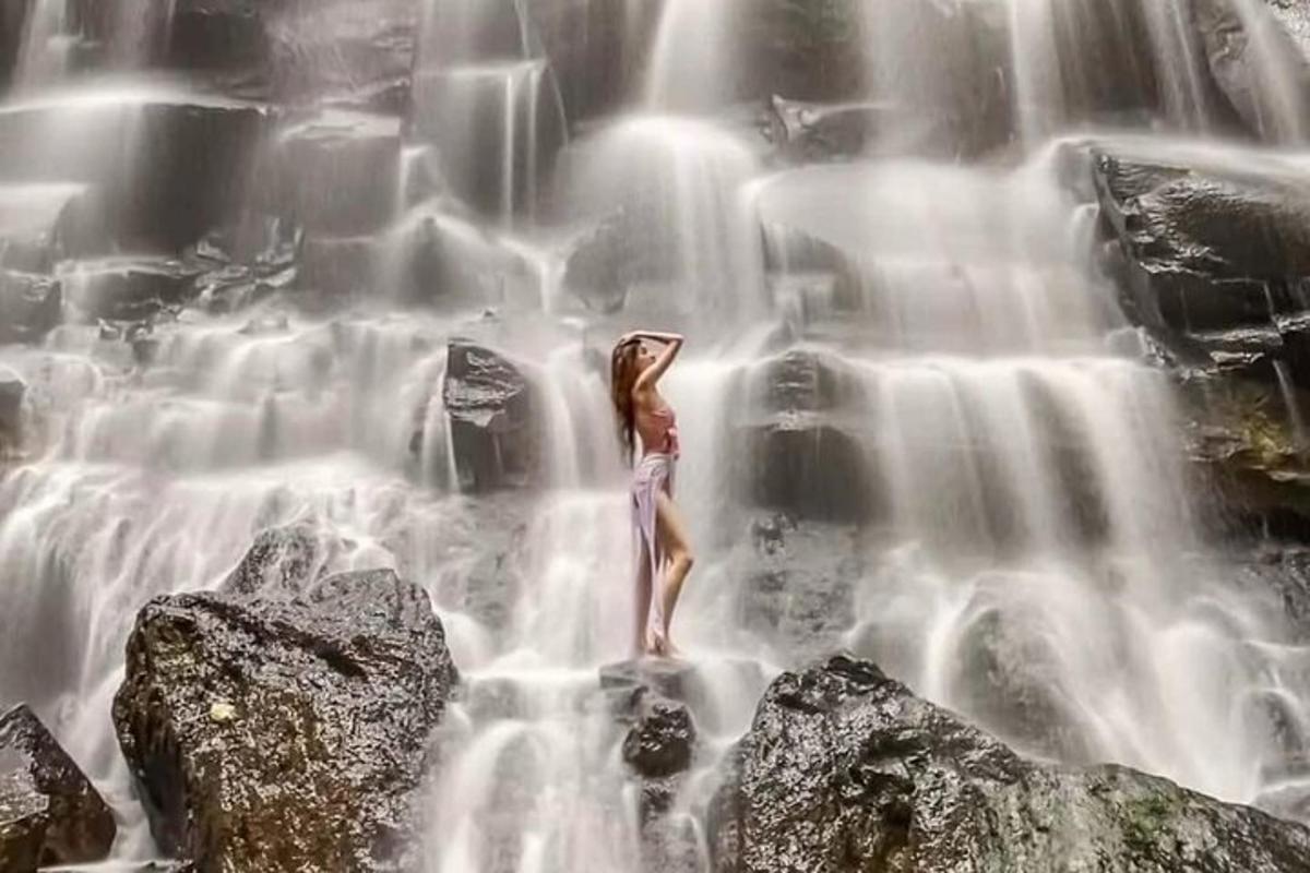 a woman standing on some rocks in a waterfall