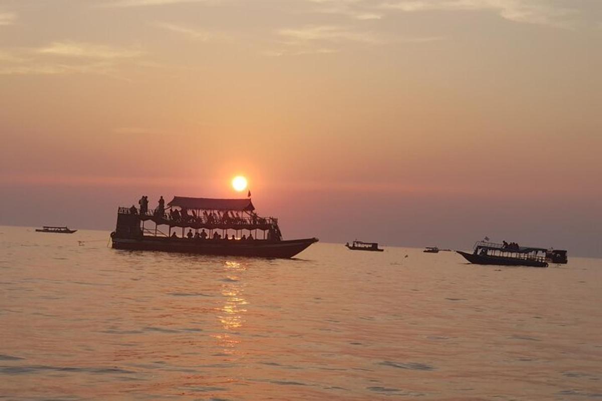 Un grupo de personas en un barco en el agua al atardecer.