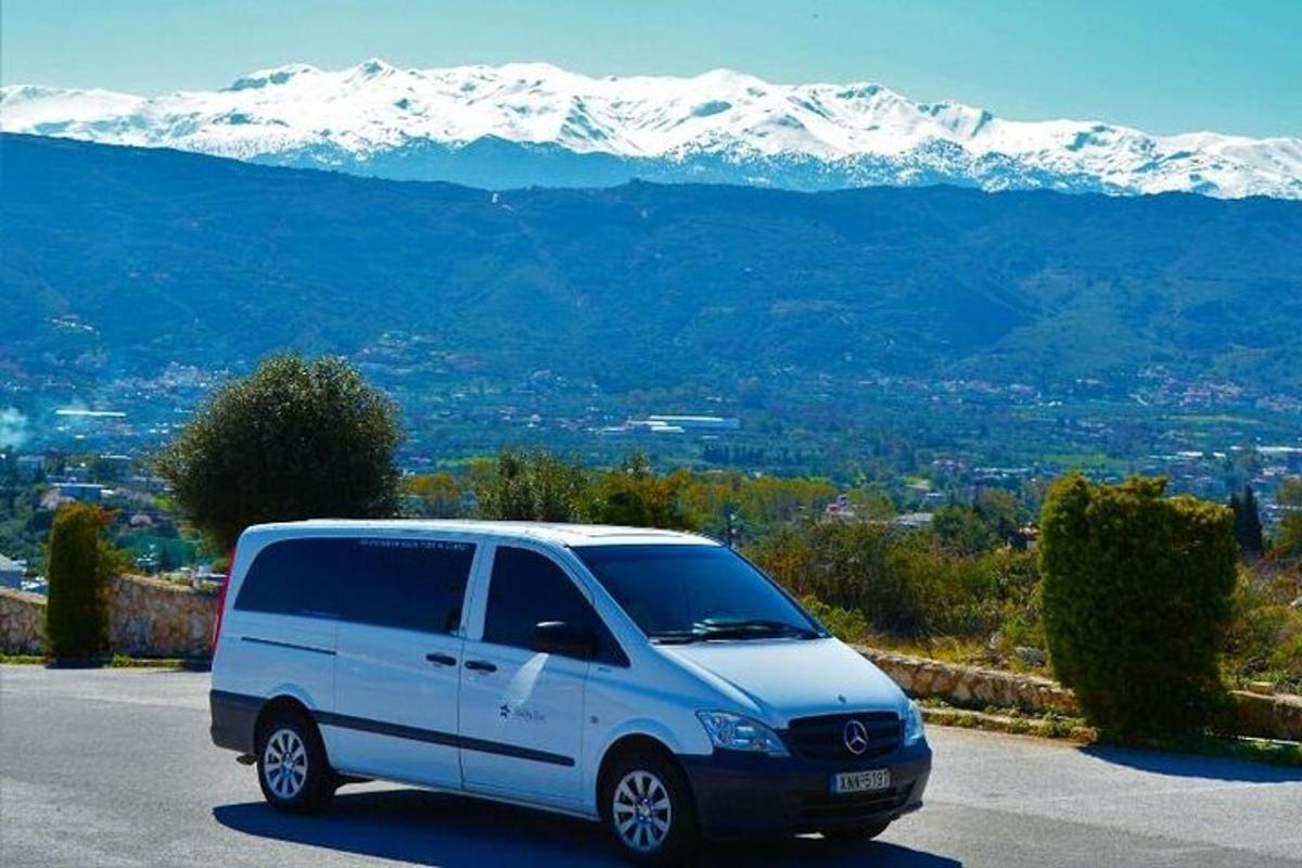 o dubă albă parcată într-o parcare cu munți acoperiți de zăpadă