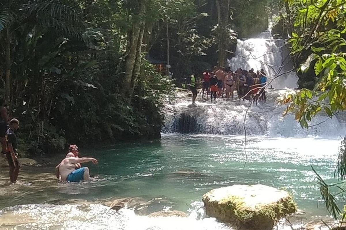 Ein Mann sitzt in einem Fluss vor einem Wasserfall