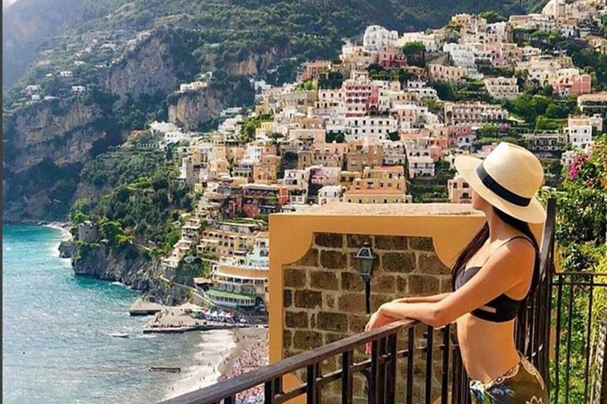Μια γυναίκα με καπέλο που κάθεται σε ένα μπαλκόνι με θέα στον ωκεανό