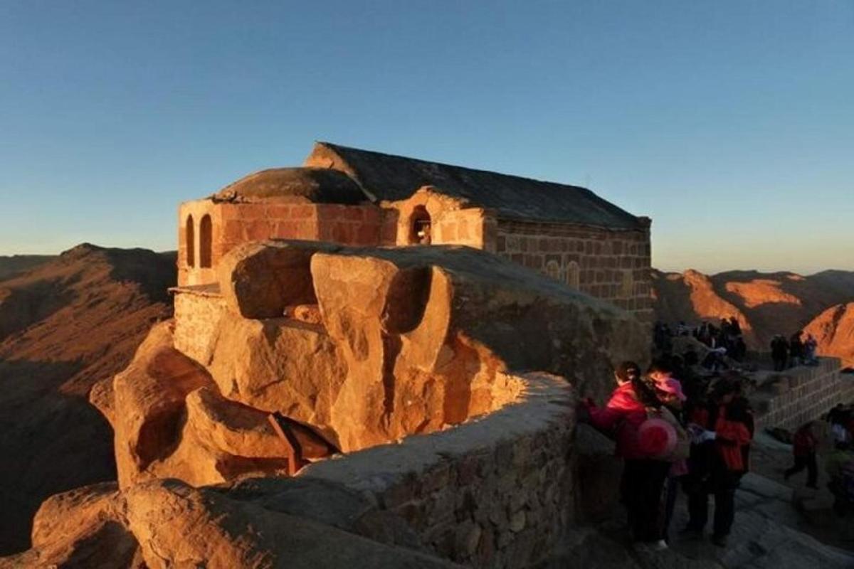 un grup de persones dempeus al voltant d'un edifici a la muntanya