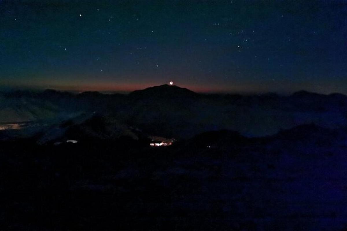 una vista notturna di una montagna con un faro in cima