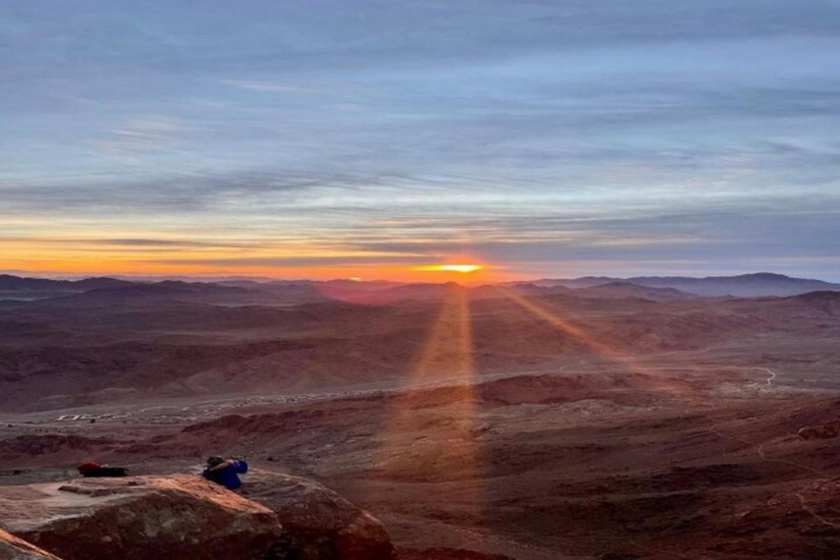 una persona seduta su una roccia che guarda il tramonto