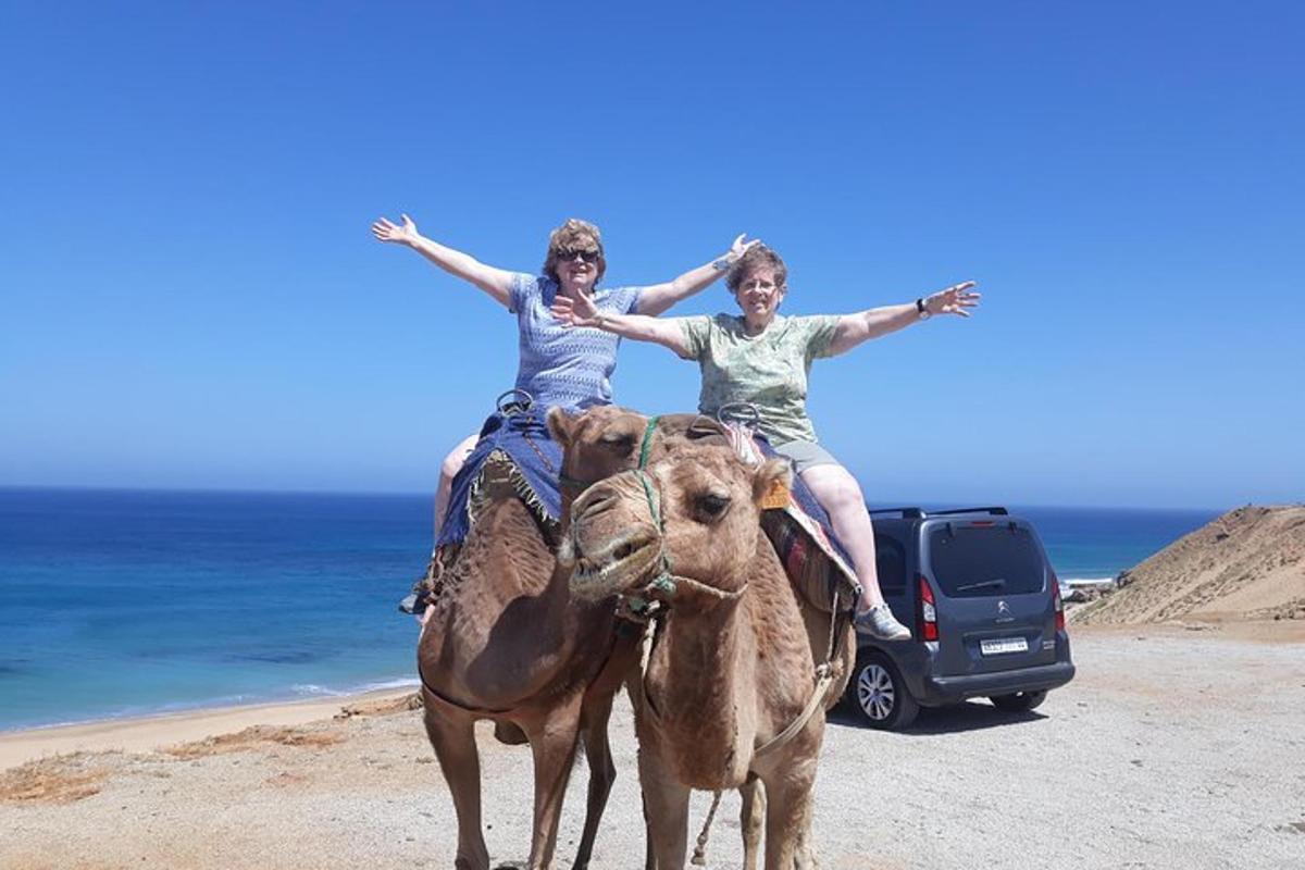 two women riding on the backs of horses on the beach