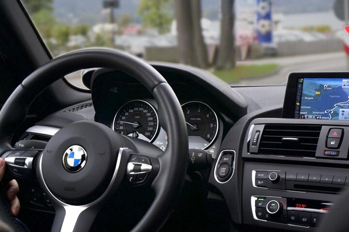 osoba řídící auto BMW s tabletem