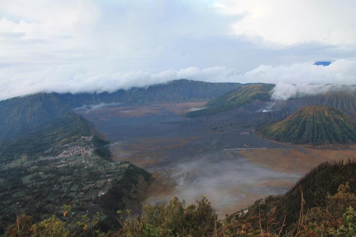 uma vista de um vale nas montanhas com nuvens
