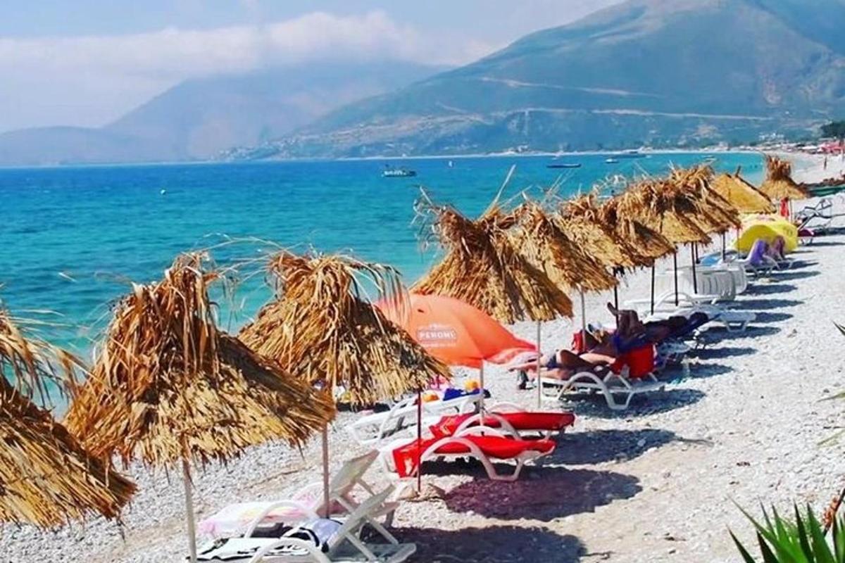 een strand met stoelen en strooien parasols en de oceaan