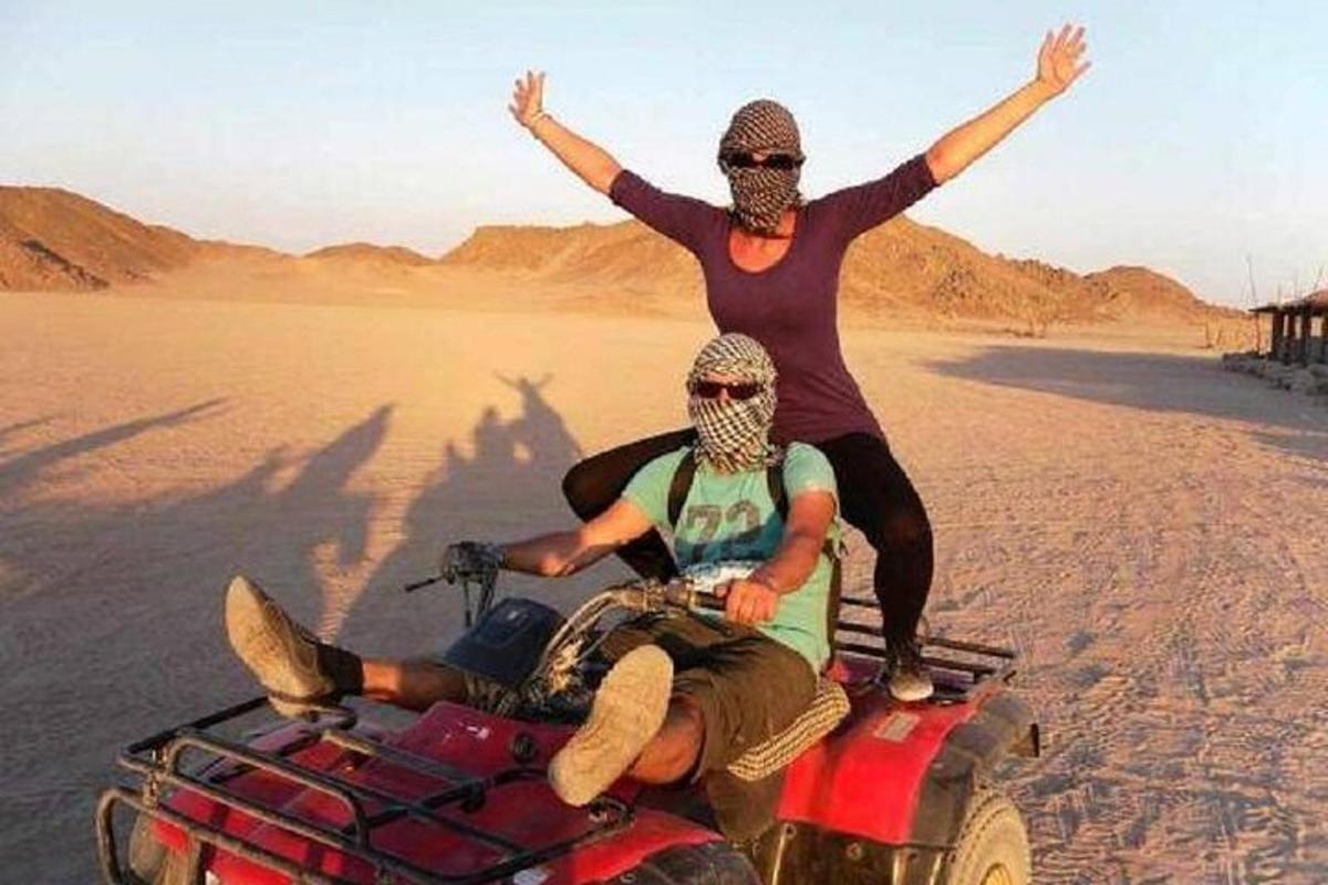 seorang wanita berdiri di atas basikal quad di padang pasir