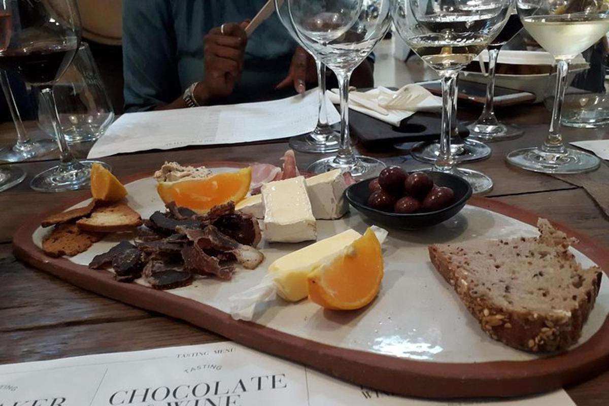 Un plato de queso y fruta en una mesa con copas de vino.